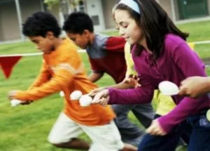 Children (10-12) having spoon and egg race (blurred motion)