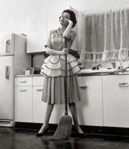1950s Woman Housewife Standing In Kitchen Leaning On Broom